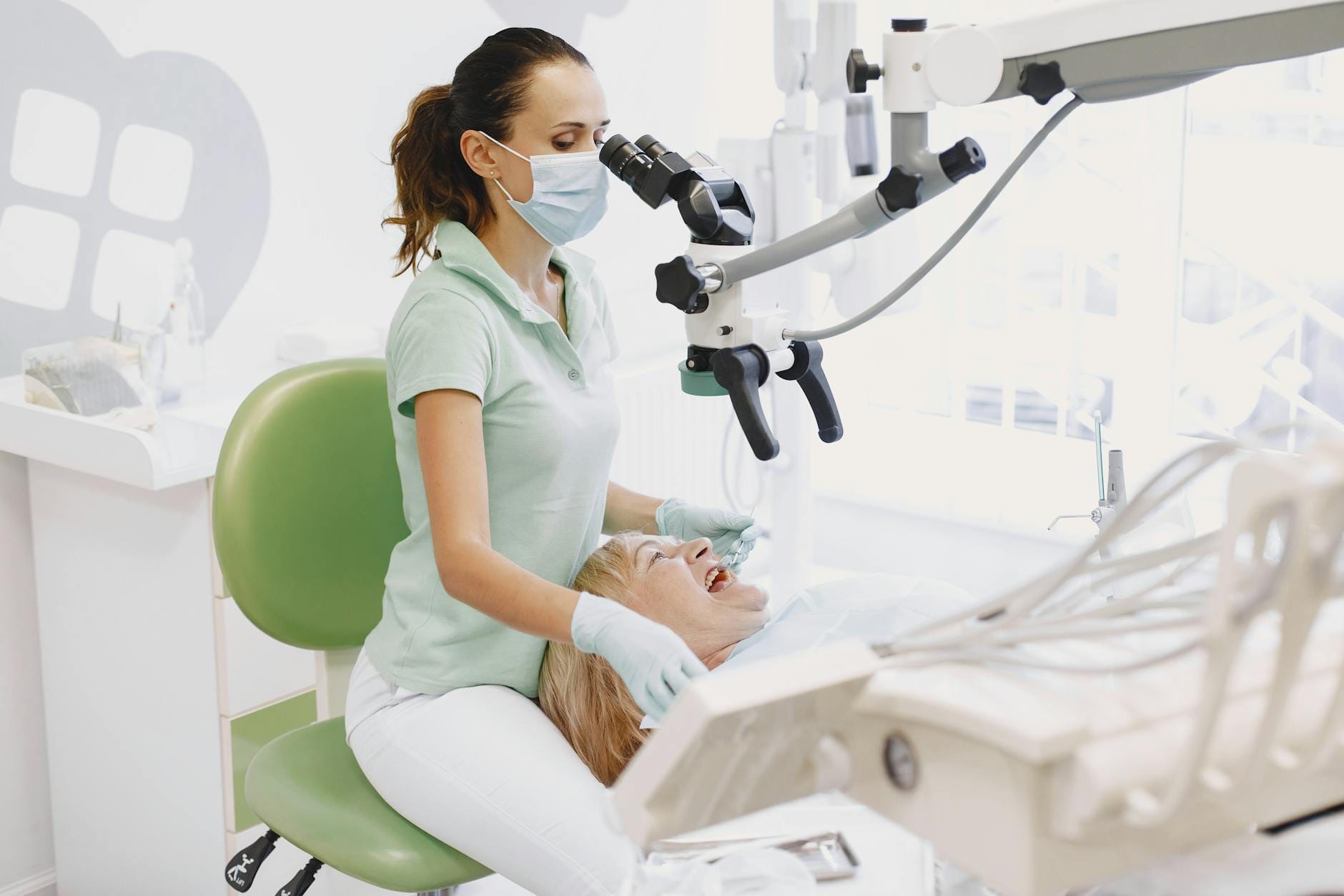 Dentysta ogląda ząb pacjenta pod mikroskopem w jasnym gabinecie