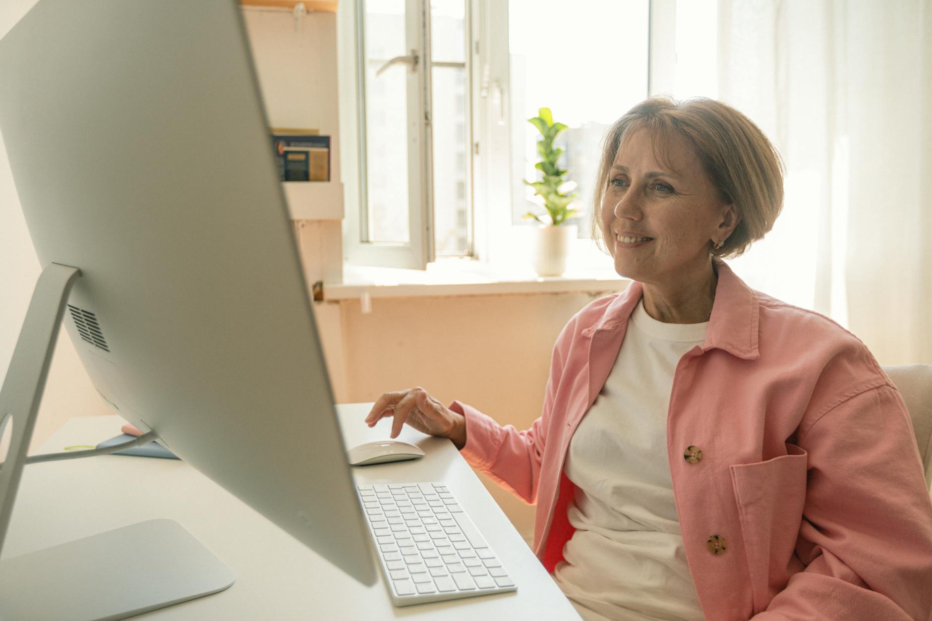 Praktyczny przewodnik po lokalnym uruchamianiu LLM: jak zbudować własną prywatną sztuczną inteligencję na domowym PC Starsza kobieta uśmiecha się, korzystając z komputera stacjonarnego w domu