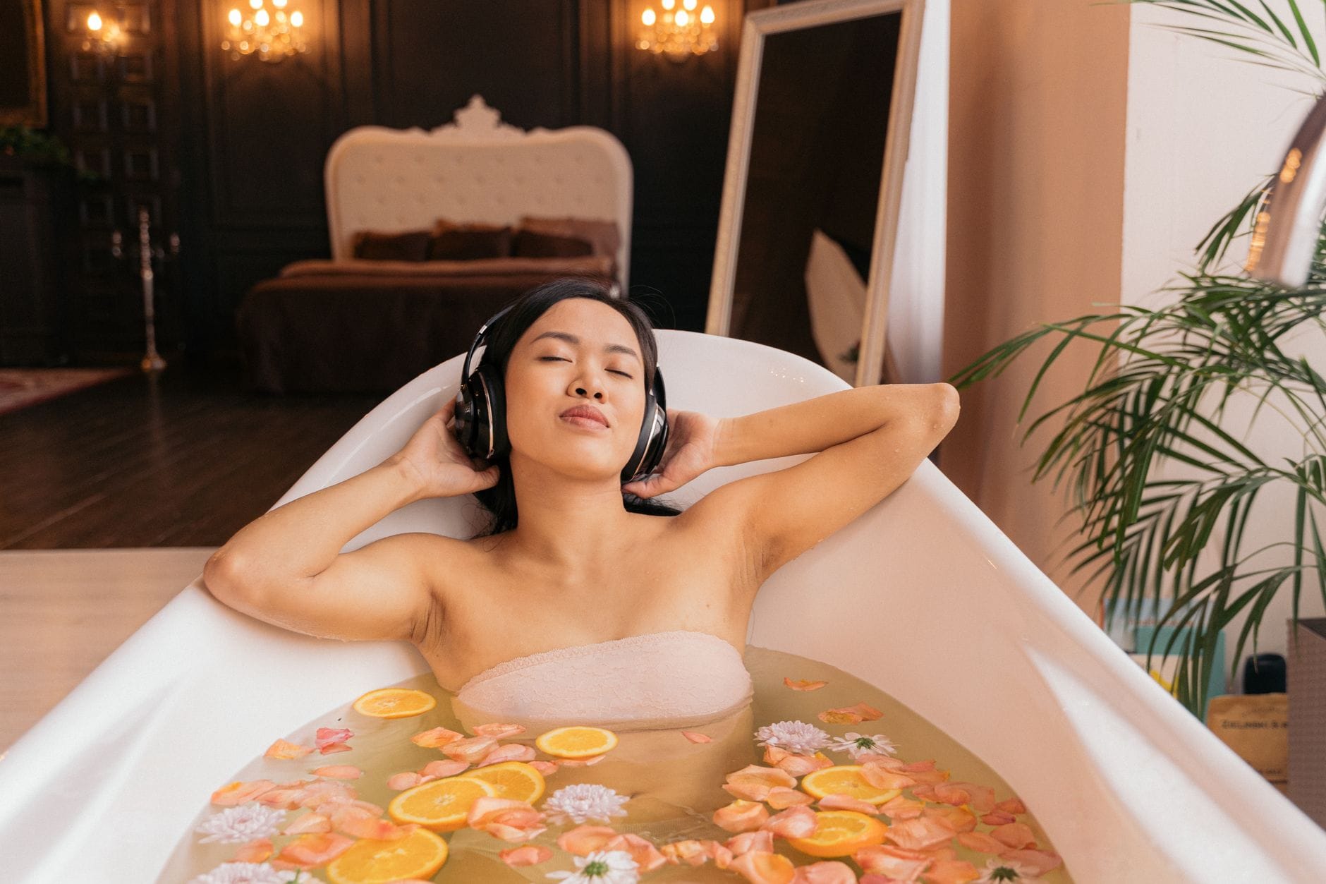 Kobieta w kwiatowej kąpieli słucha muzyki w słuchawkach w domowym SPA